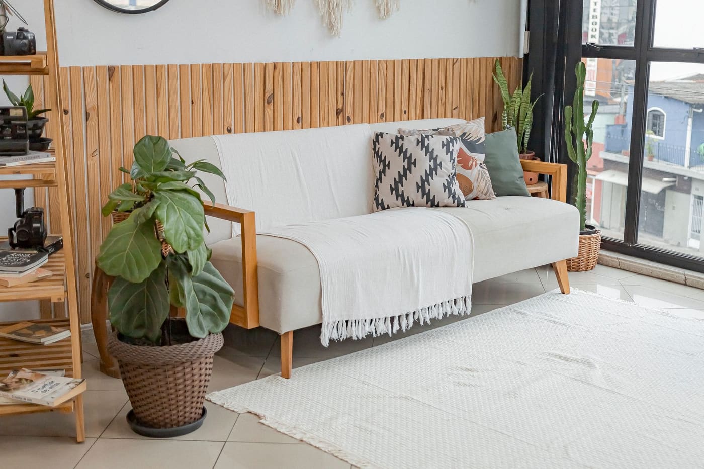 A bright living room with a white sofa, wood paneling and large indoor plants