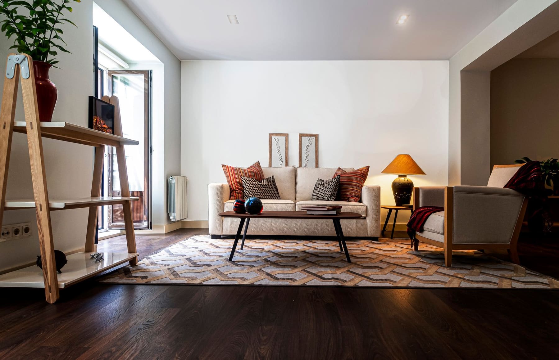 A bright living room with a sofa, warm lamp, rug and framed pictures