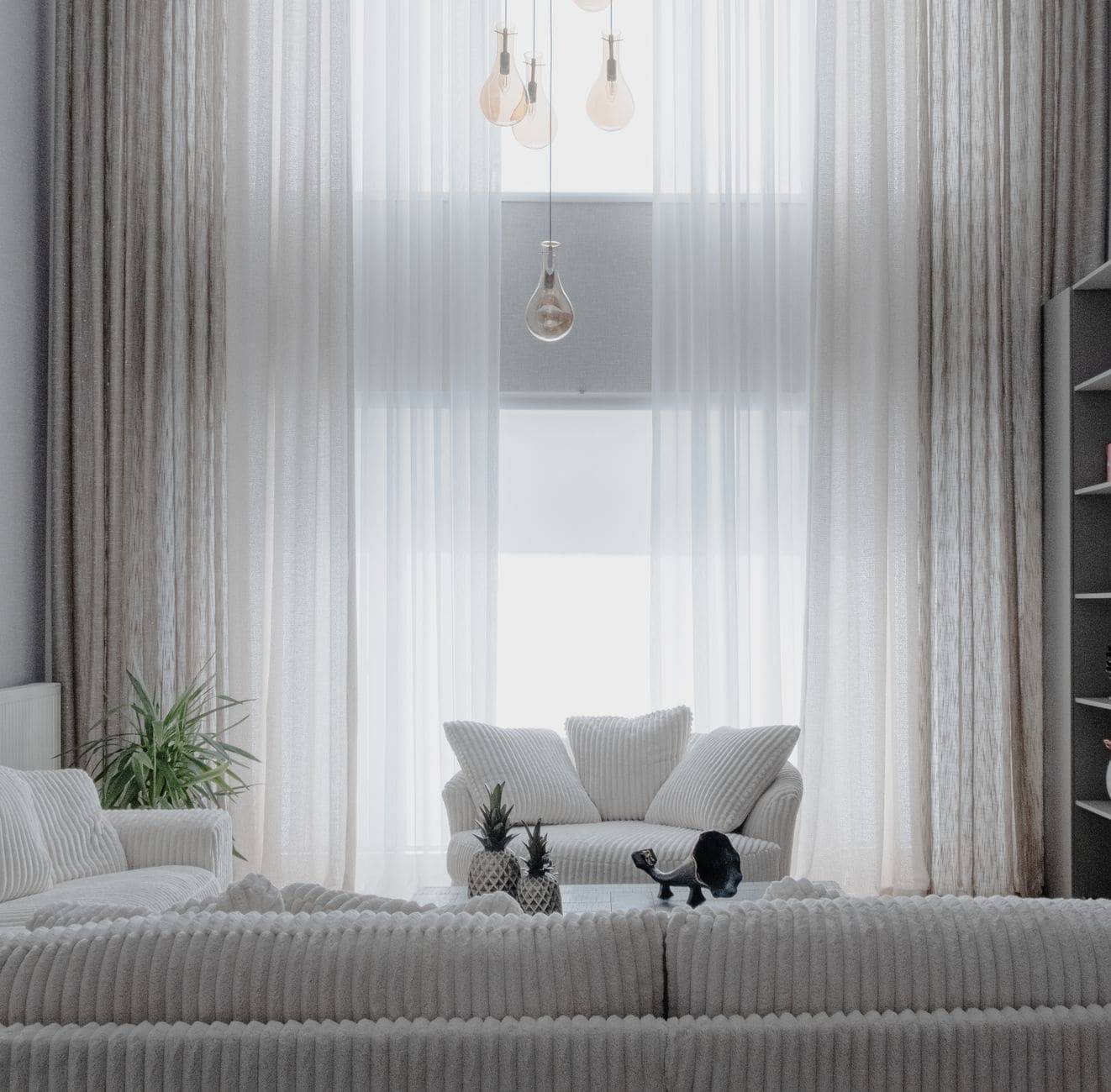 A bright minimalist living room with white sofas and tall sheer curtains